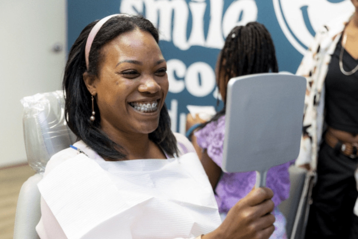 Patient smiling with braces while checking results in mirror at Glass Orthodontics in Chesapeake VA