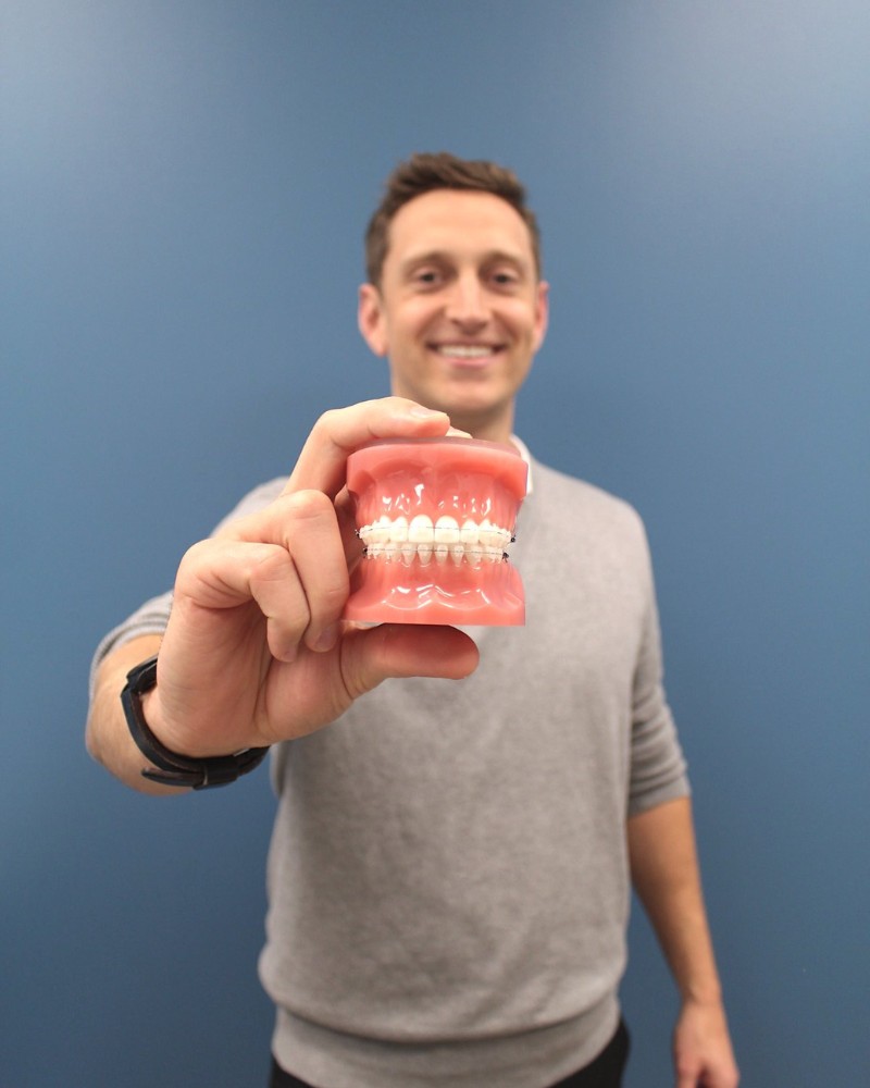 Clear Ceramic Braces Option Orthodontist holding model of ceramic braces in Chesapeake VA at Glass Orthodontics