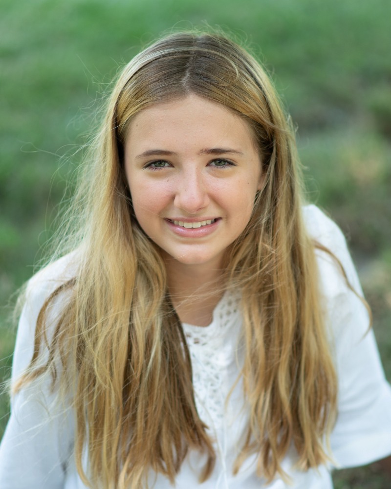 Teen orthodontic patient smiling outdoors with improved smile in Chesapeake Virginia